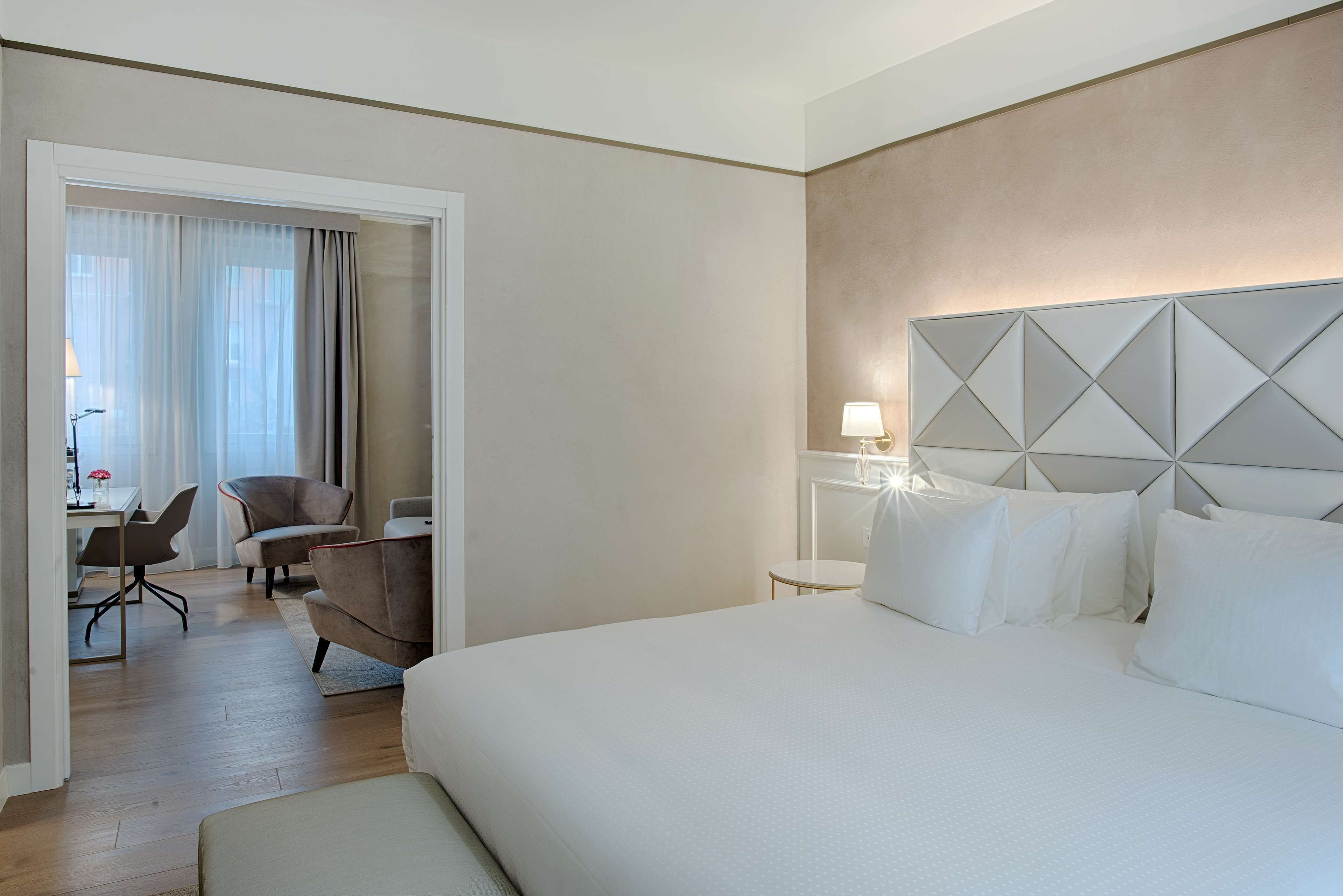 Une chambre d’hôtel avec un grand lit, un bureau avec une chaise et une vue sur l’extérieur par une porte.