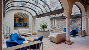 A spacious indoor area with a glass ceiling, seating arrangements, and a central plant. - NH Collection Palazzo Verona (Verona)