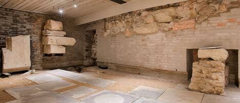 Un interior con paredes de ladrillo visto, pilares de piedra y un suelo de baldosas con diseños geométricos.