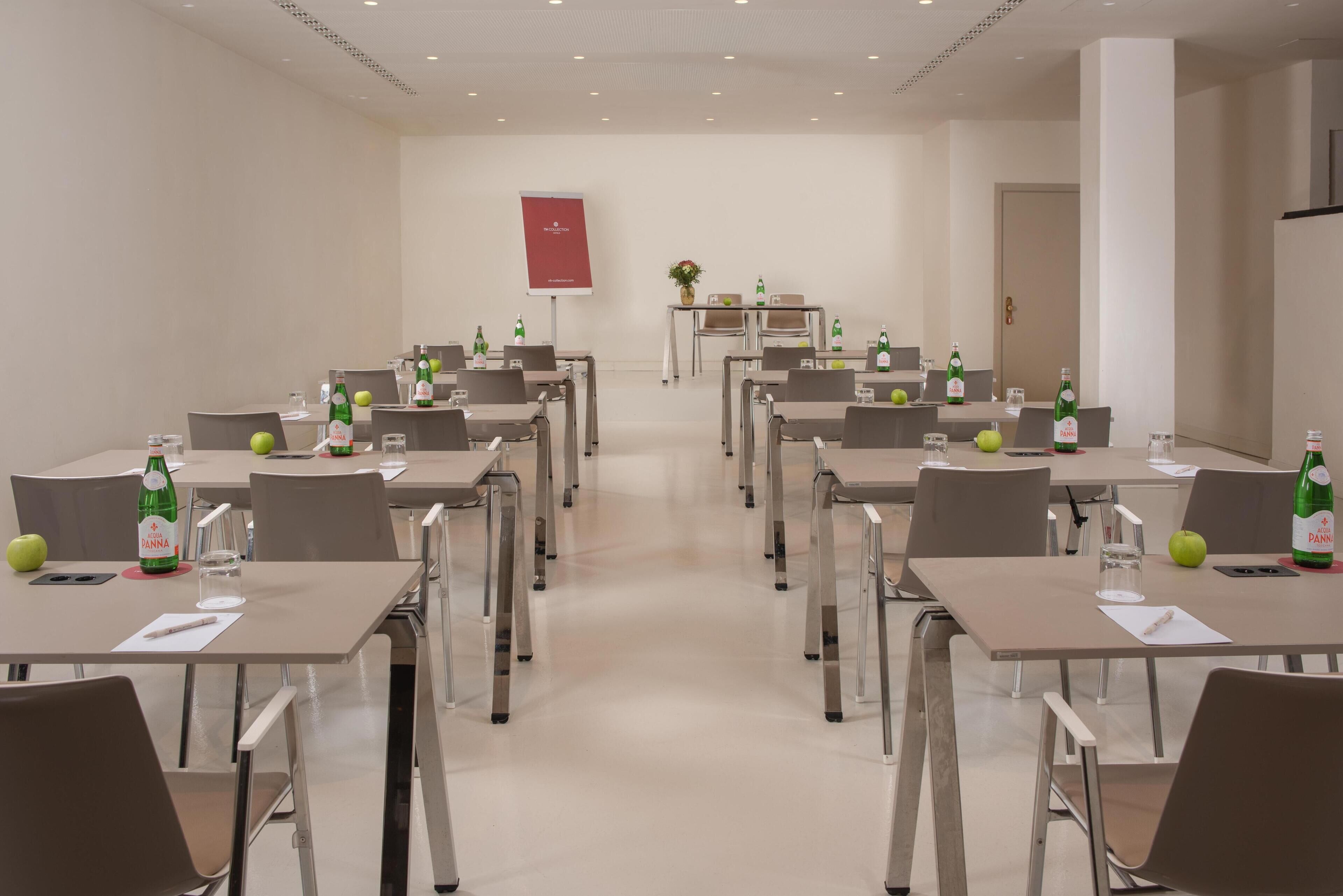 A conference room with tables, chairs, and bottles of water.