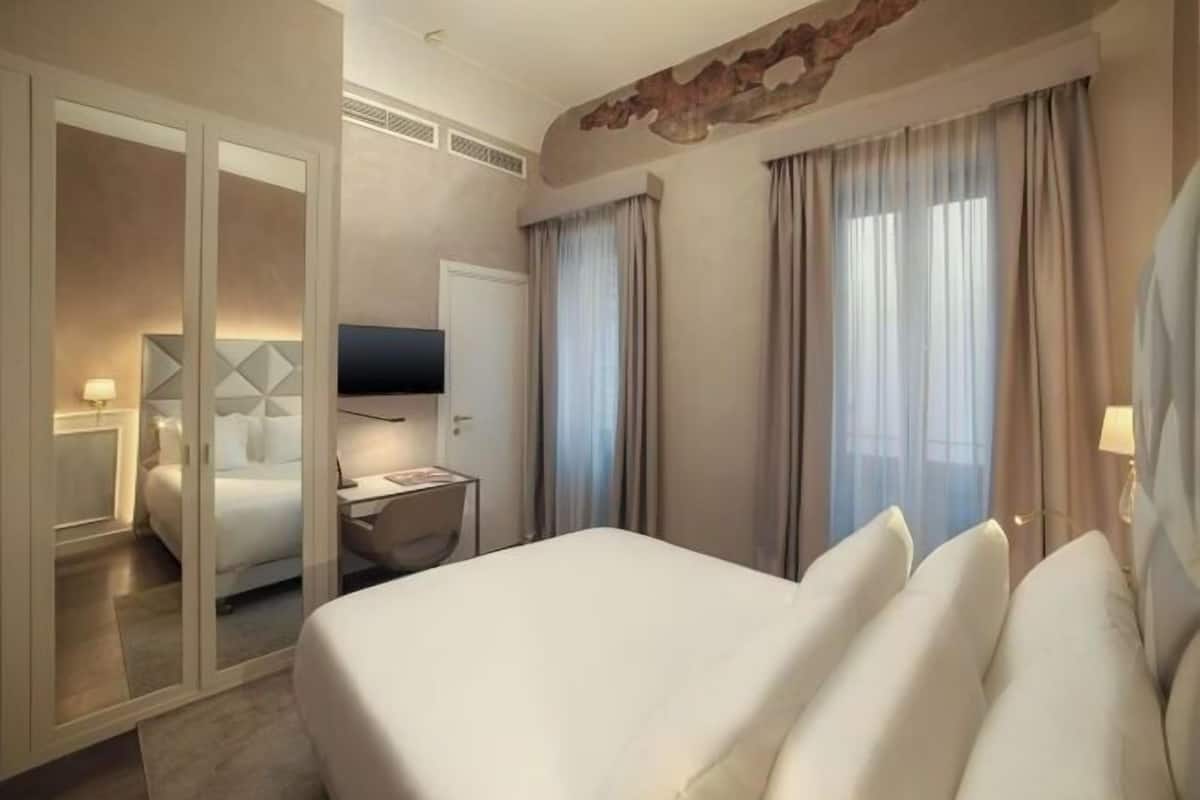 Une chambre d’hôtel avec un grand lit, une télévision, un bureau et une armoire.