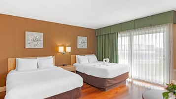 A hotel room with two beds, a round table, and a large window with sheer curtains.
