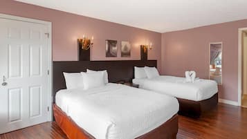 Une chambre d’hôtel avec deux lits, une porte blanche et des appliques murales.