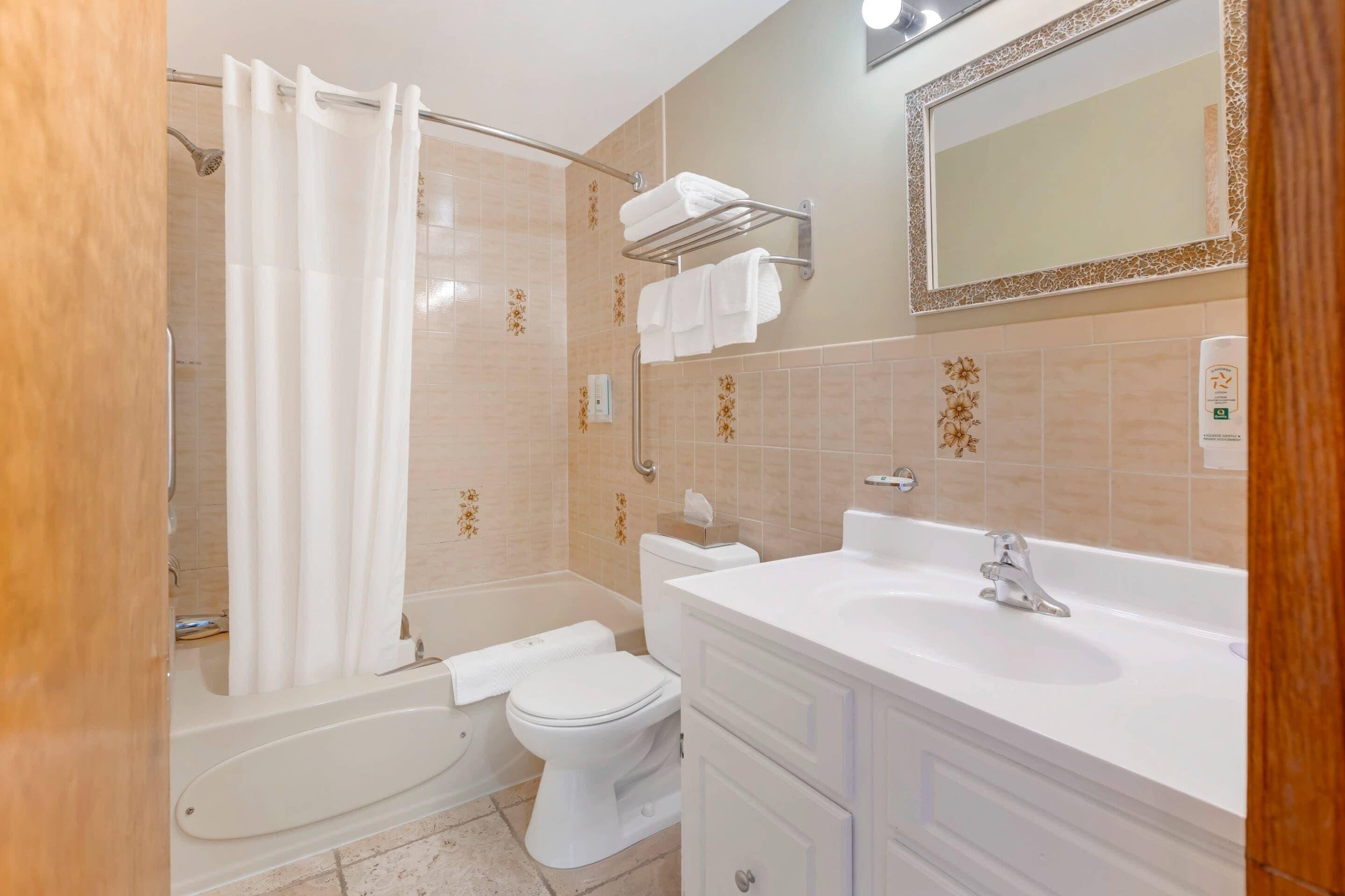 A bathroom with a bathtub, toilet, and vanity with a sink.