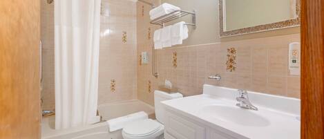 A bathroom with a bathtub, toilet, and vanity with a sink.