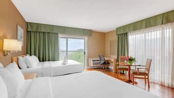 Une chambre d’hôtel avec un grand lit, un bureau, deux chaises, une lampe et une fenêtre avec des rideaux.