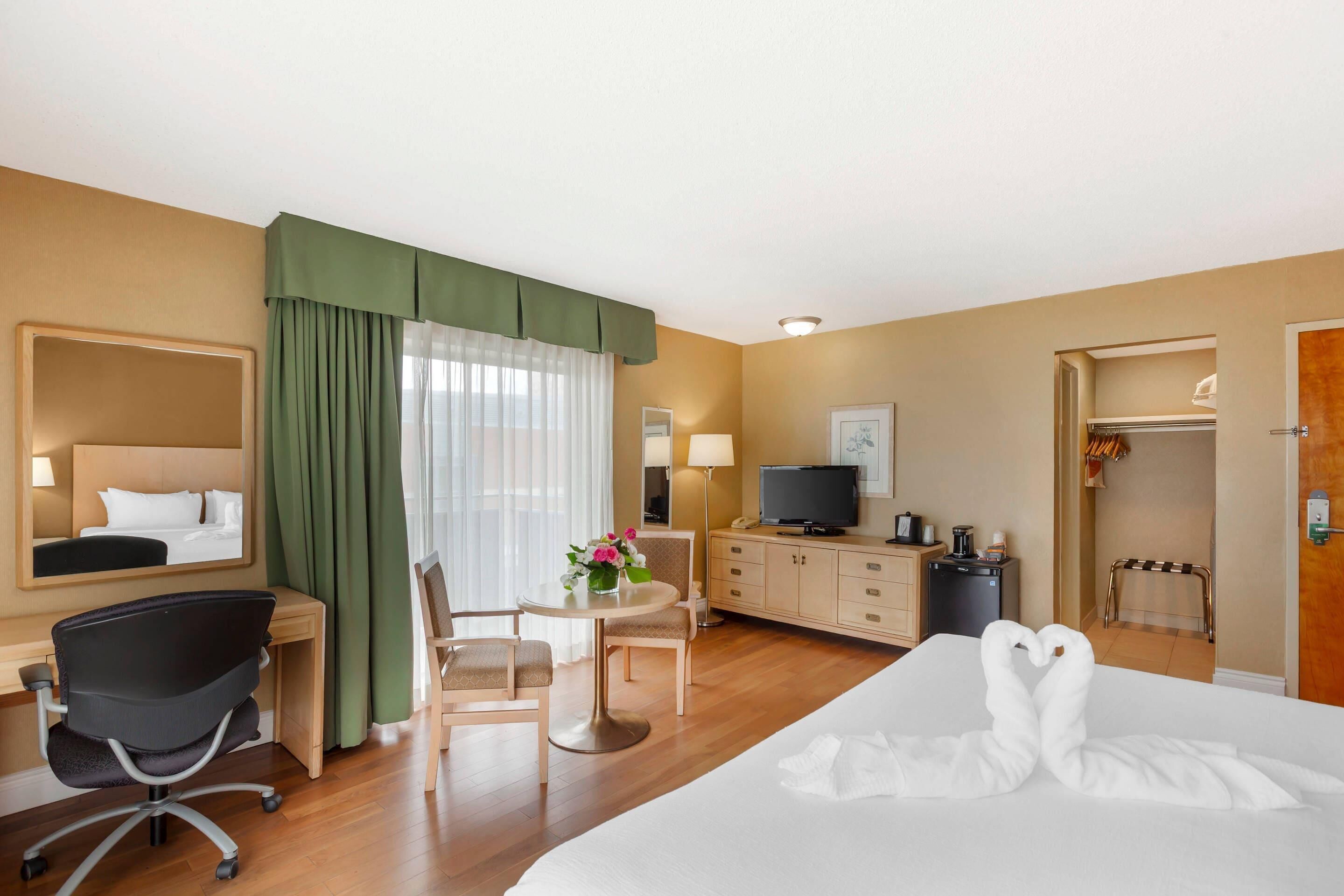 A hotel room with a bed, desk, chair, television, and a closet.