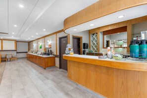 A modern hotel reception area with a wooden reception desk, a coffee machine, and a water dispenser. - Quality Hotel Fallsview Cascade (Niagara Falls)