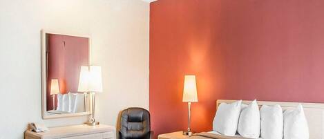 Une chambre d’hôtel comprenant un lit, des lampes de chevet, un bureau avec un téléphone, une chaise et un miroir.