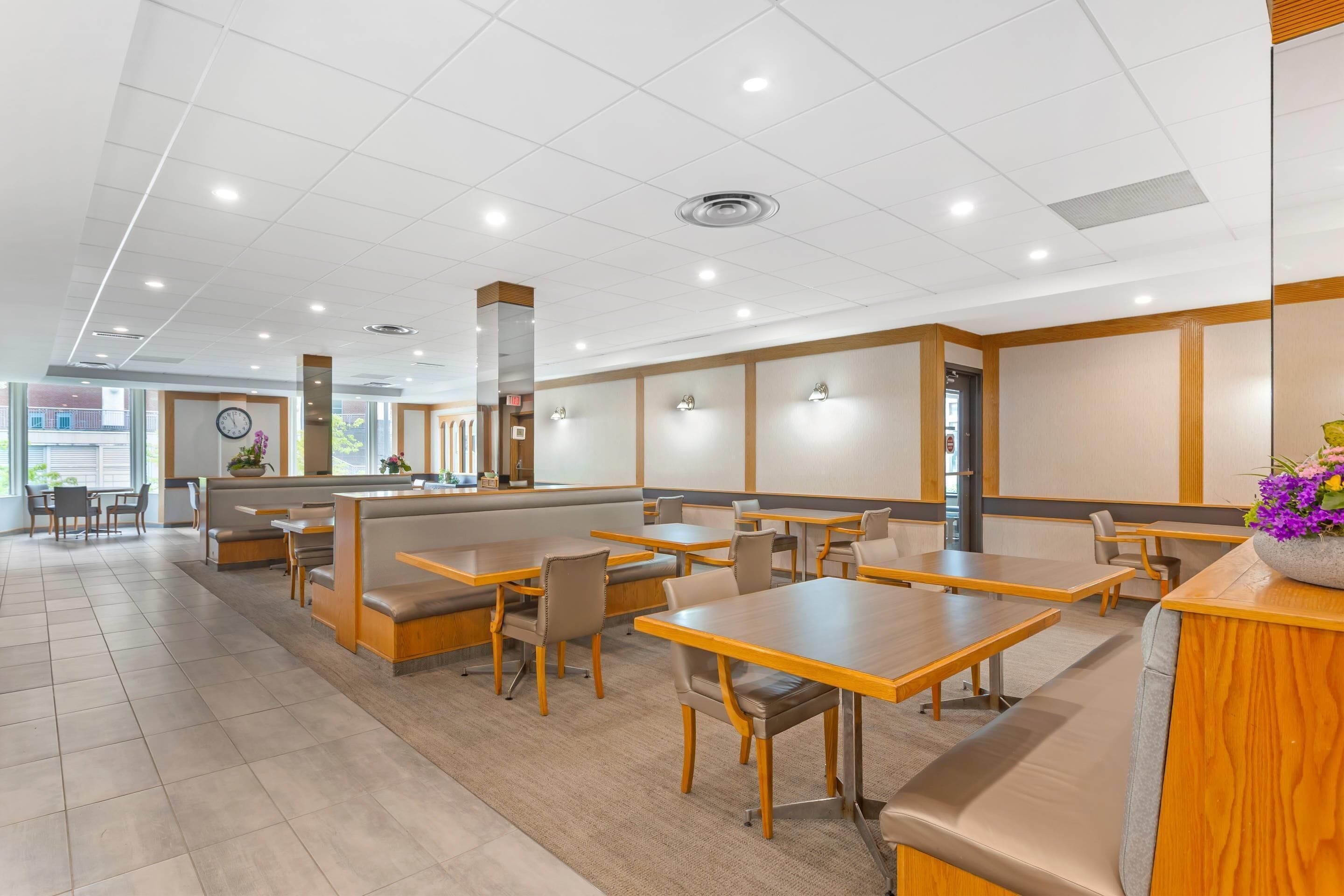 Un restaurante espacioso con techos altos, iluminación empotrada y una combinación de mesas y cabinas.