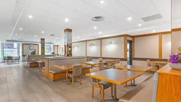 Un restaurante espacioso con techos altos, iluminación empotrada y una combinación de mesas y cabinas.