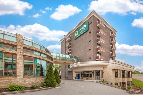 A hotel with a modern design, featuring a glass walkway and a prominent sign.
