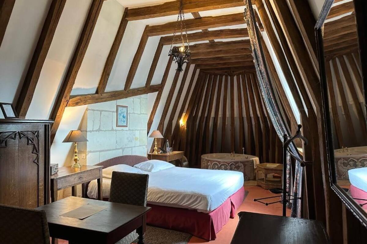Une chambre confortable située dans les combles, avec des poutres apparentes, un lit, un bureau et une chaise.