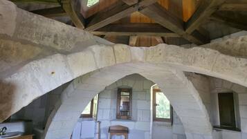 A rustic room with exposed wooden beams, stone walls, and a small window.