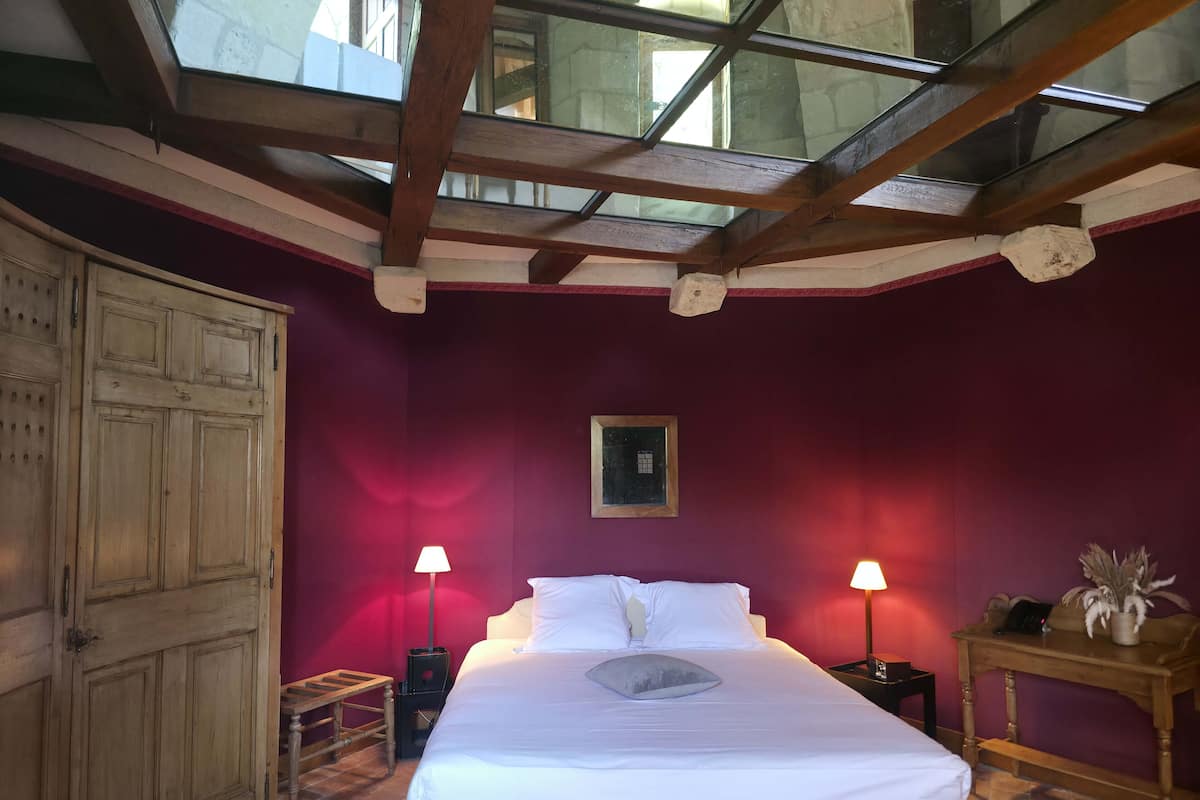 Une chambre à coucher avec un grand lit, deux lampes de chevet, une armoire en bois et une lucarne.
