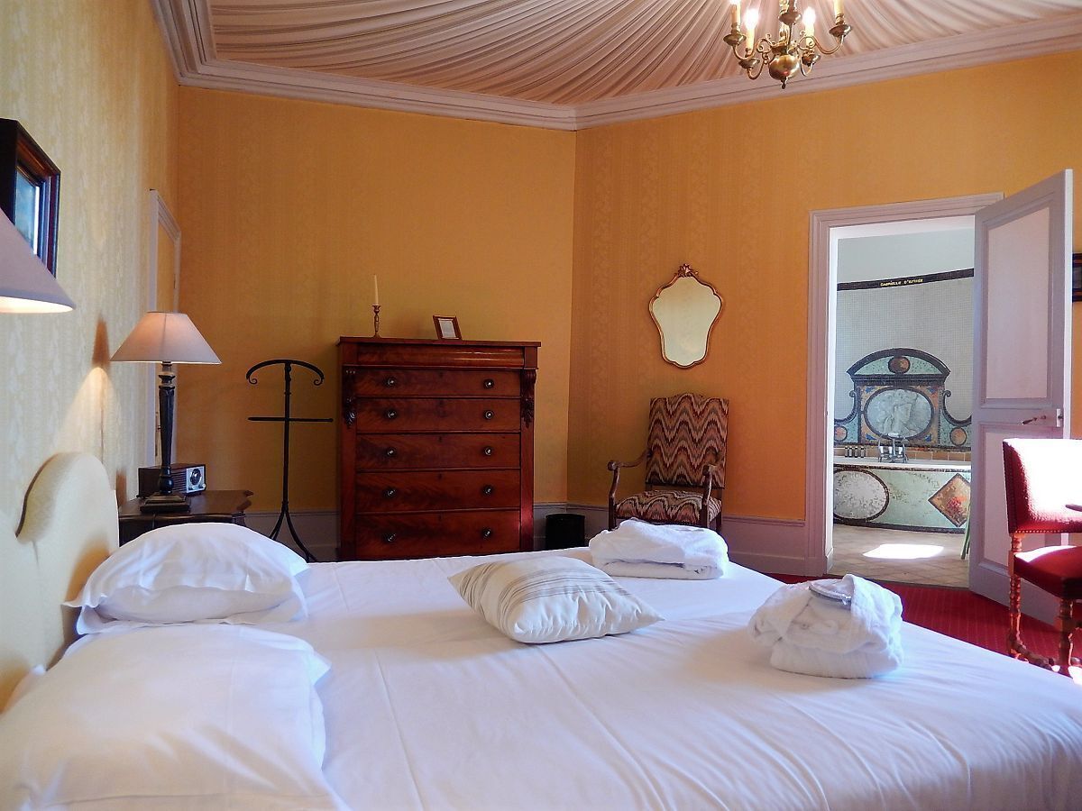 A hotel room with a large bed, a dresser, a chair, and a view of the outside.