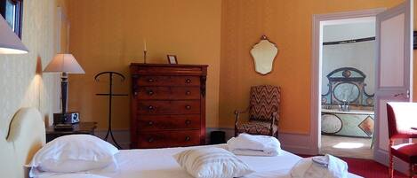 A hotel room with a large bed, a dresser, a chair, and a view of the outside.