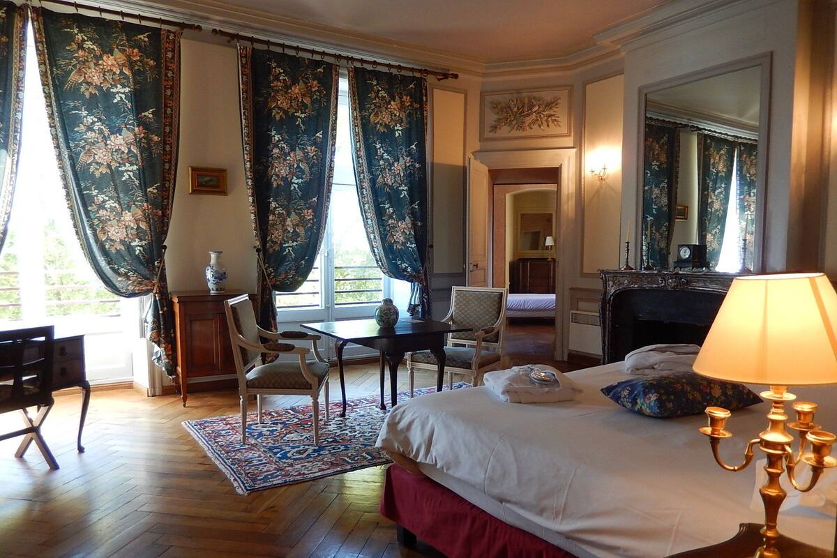 Une chambre d’hôtel avec un lit, un bureau, une chaise, une table et une lampe.