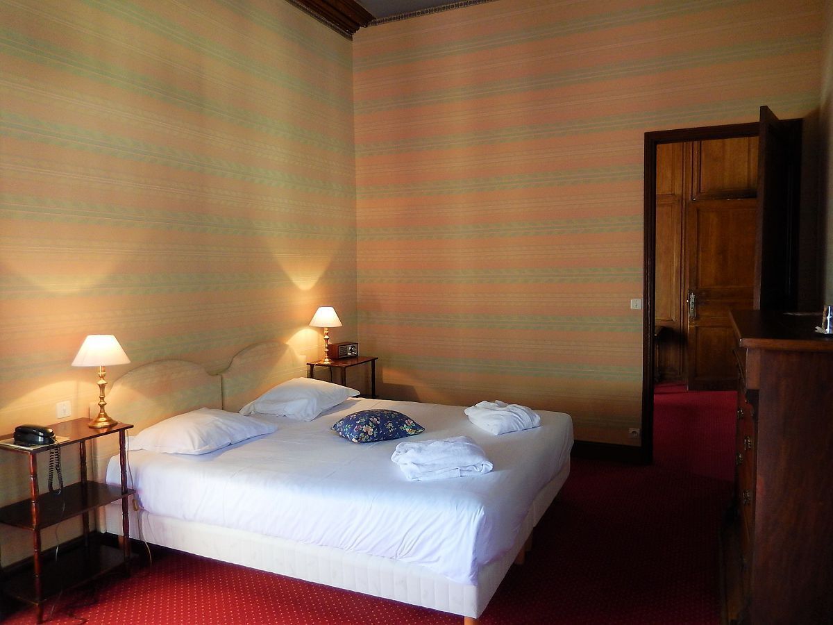 Ein Hotelzimmer mit einem Bett, zwei Nachttischlampen, einem Holzschrank und einem roten Teppich.