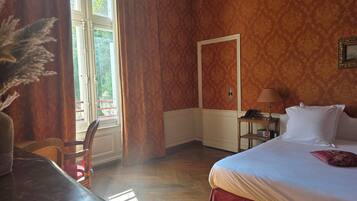 Camera d'albergo con un letto, una scrivania, una sedia, una lampada e una finestra con tende.