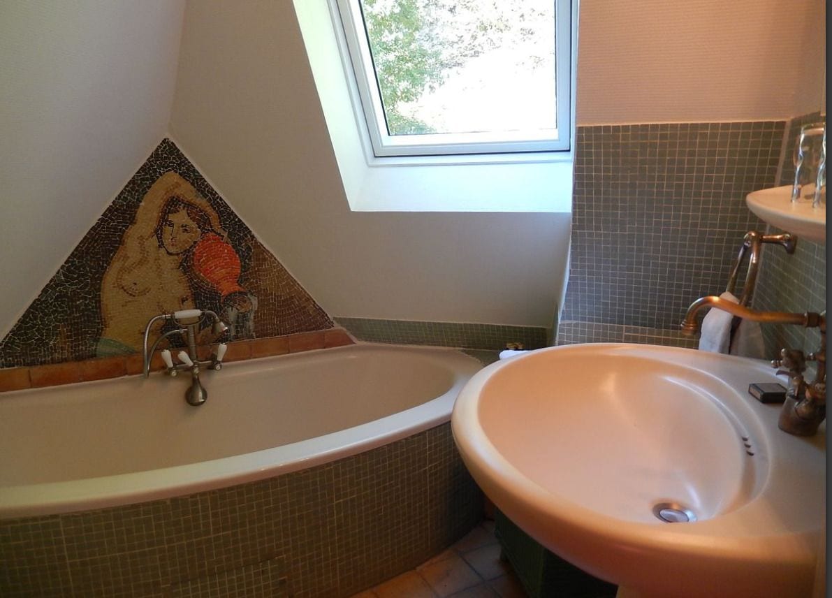 A bathroom with a mosaic wall, a bathtub, and a sink.