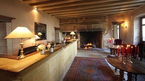 Una habitación con chimenea, techo de madera, revestimiento de piedra alrededor de la chimenea, una mesa con velas y una alfombra.