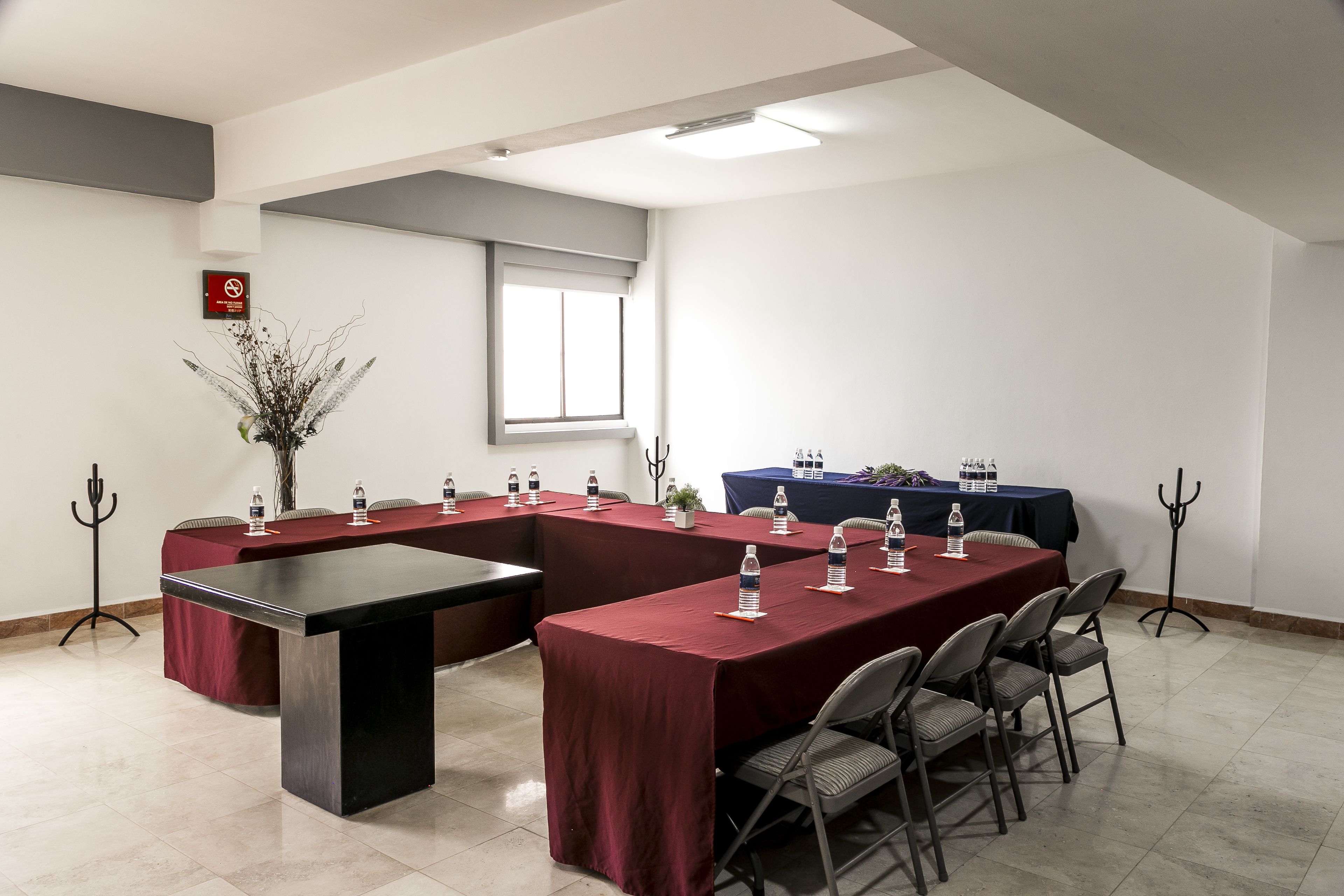 Une salle de conférence avec une longue table, des chaises et des bouteilles d’eau.