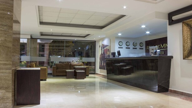A modern lobby with a reception desk, seating area, and a glass partition.