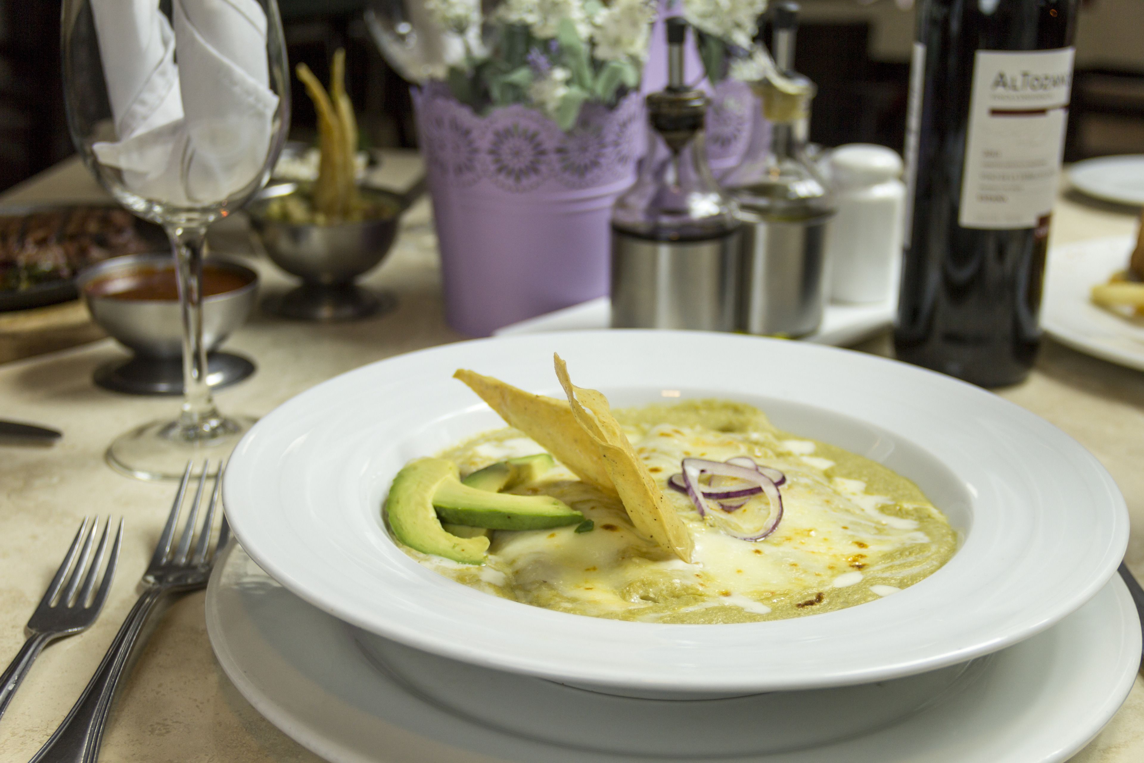 A plate of food with avocado and a tortilla chip on a white plate.