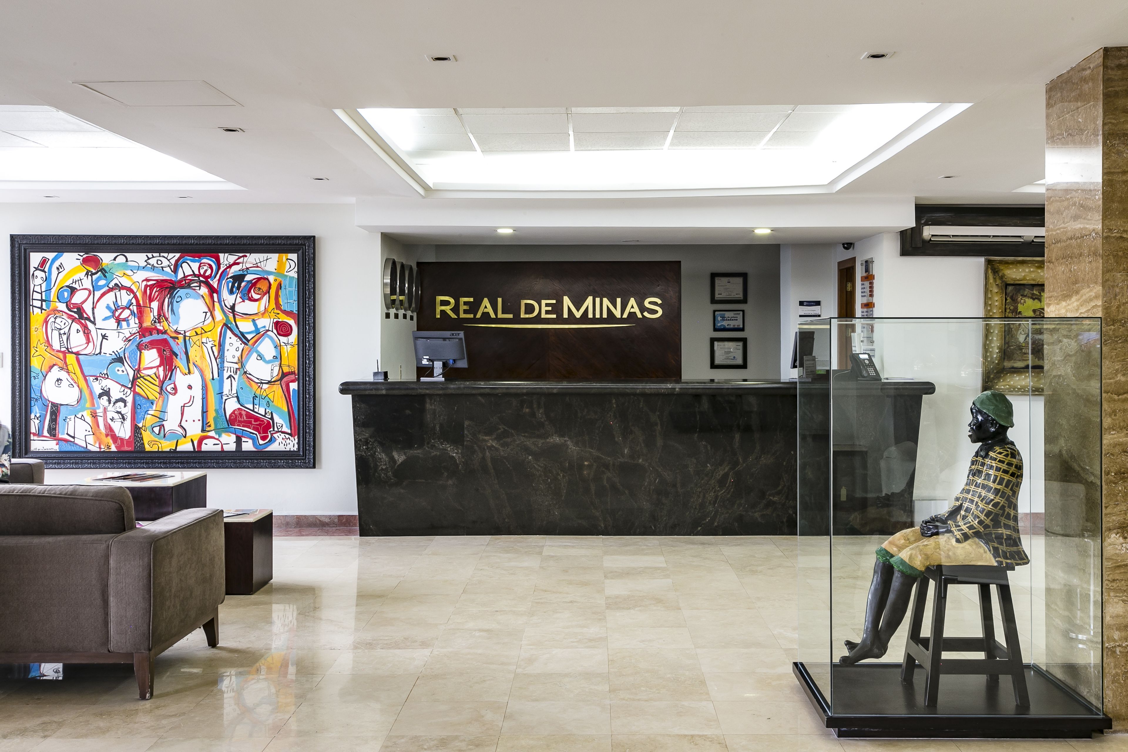 A reception area with a marble counter, a colorful abstract painting, and a statue.