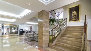 A spacious lobby with a marble staircase, a large mirror, and a statue.