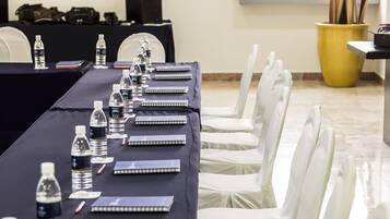 A conference room with a long table, white chairs, water bottles, notebooks, and a framed picture on the wall.