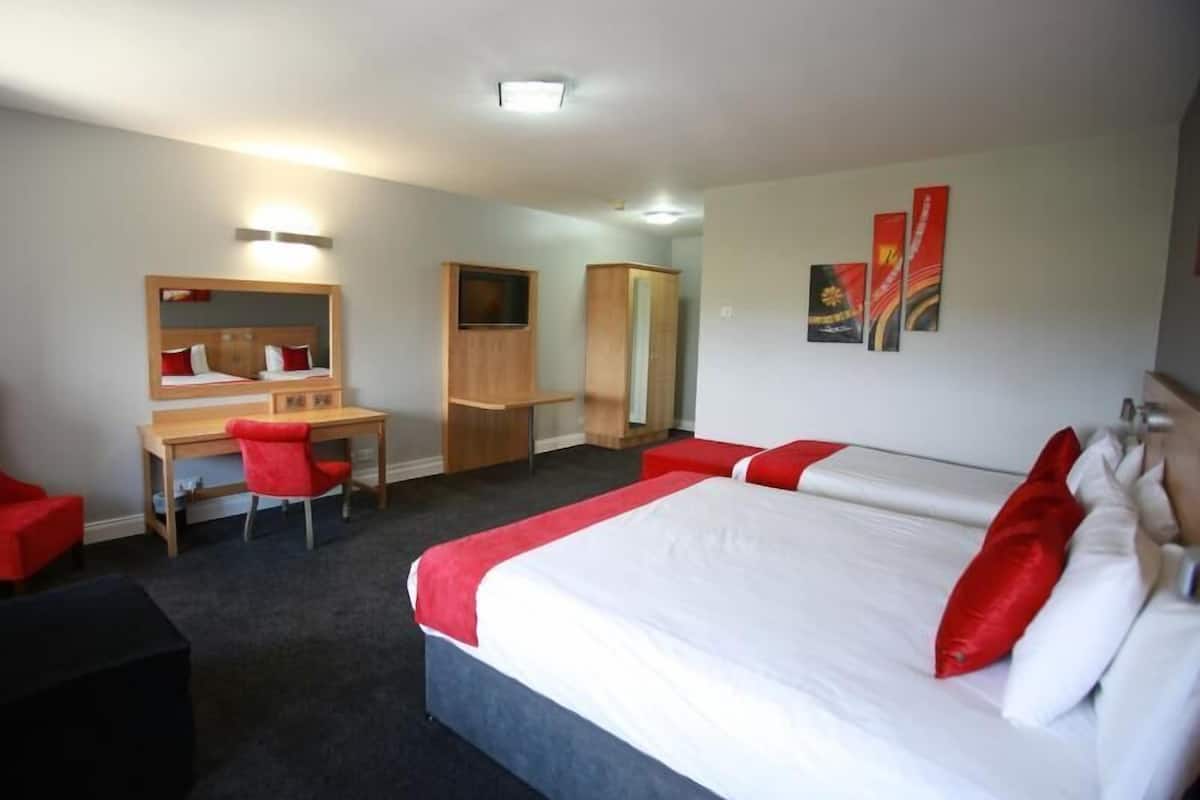 Habitación de hotel con cama, escritorio, silla, armario y espejo.