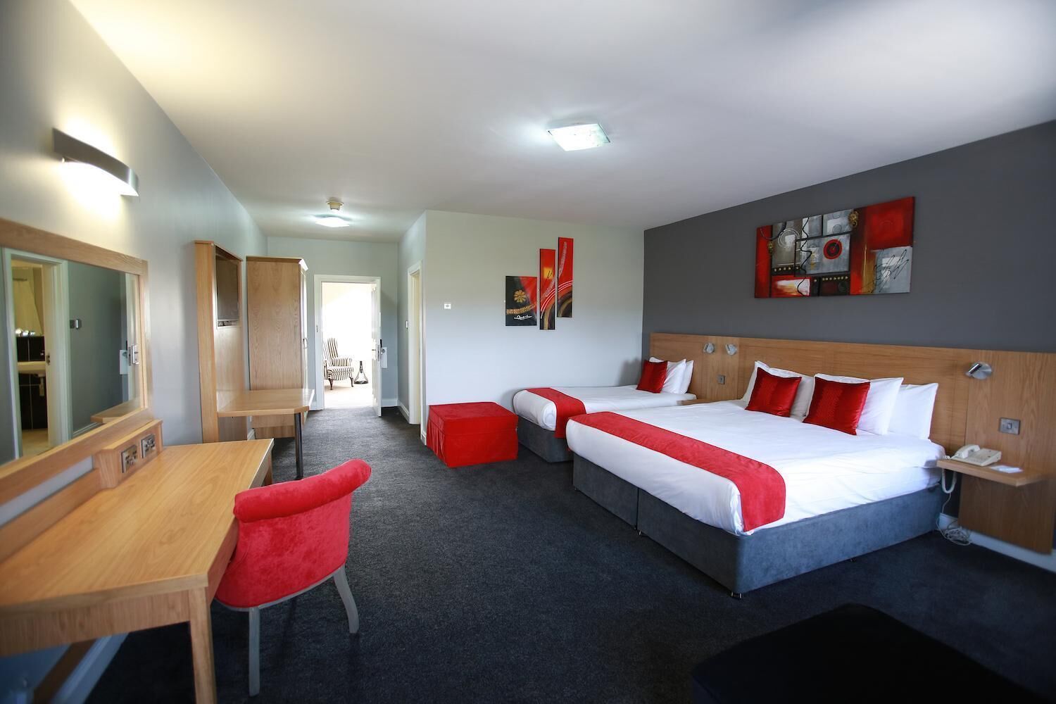 A hotel room with two beds, a desk, a chair, and a TV.