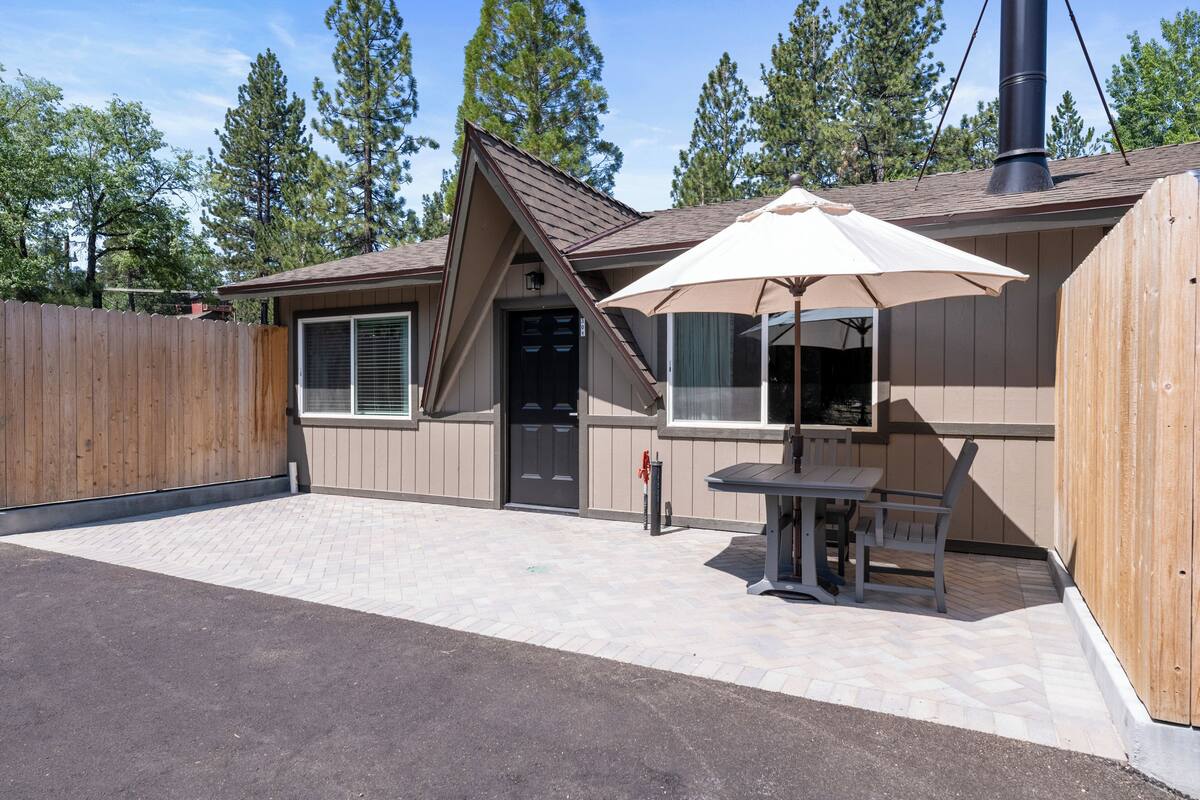 A single-story building with a covered patio area, a wooden fence, and a chimney.