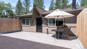A single-story building with a covered patio area, a wooden fence, and a chimney.