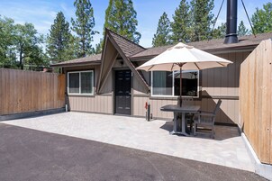 A single-story building with a covered patio area, a wooden fence, and a chimney.