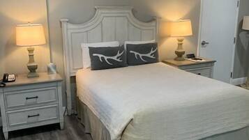 A bedroom with a bed, two bedside tables, and a door.