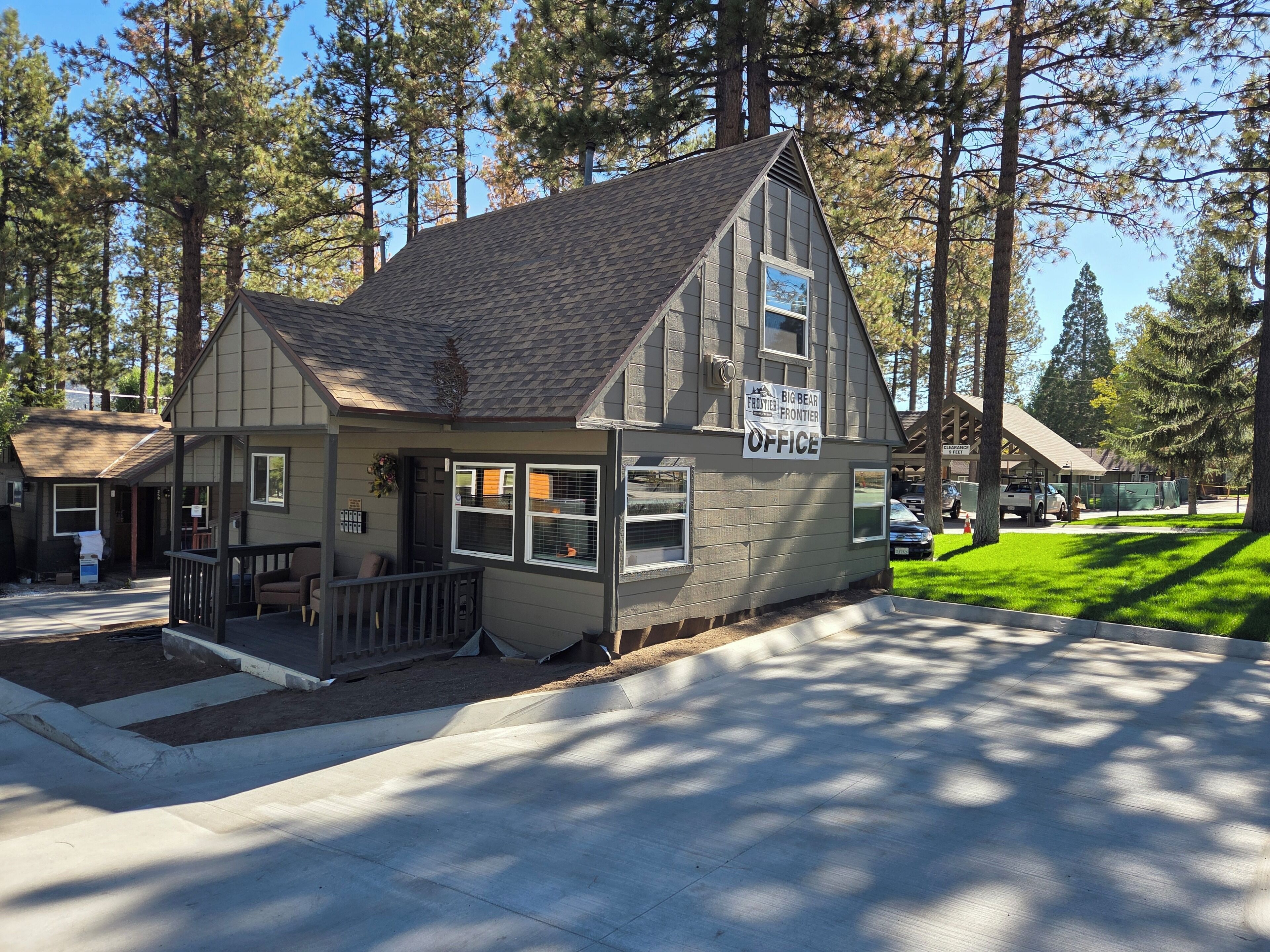 A small office building with a gabled roof, a porch with a bench, and a sign indicating it is an office.