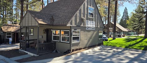 A small office building with a gabled roof, a porch with a bench, and a sign indicating it is an office.