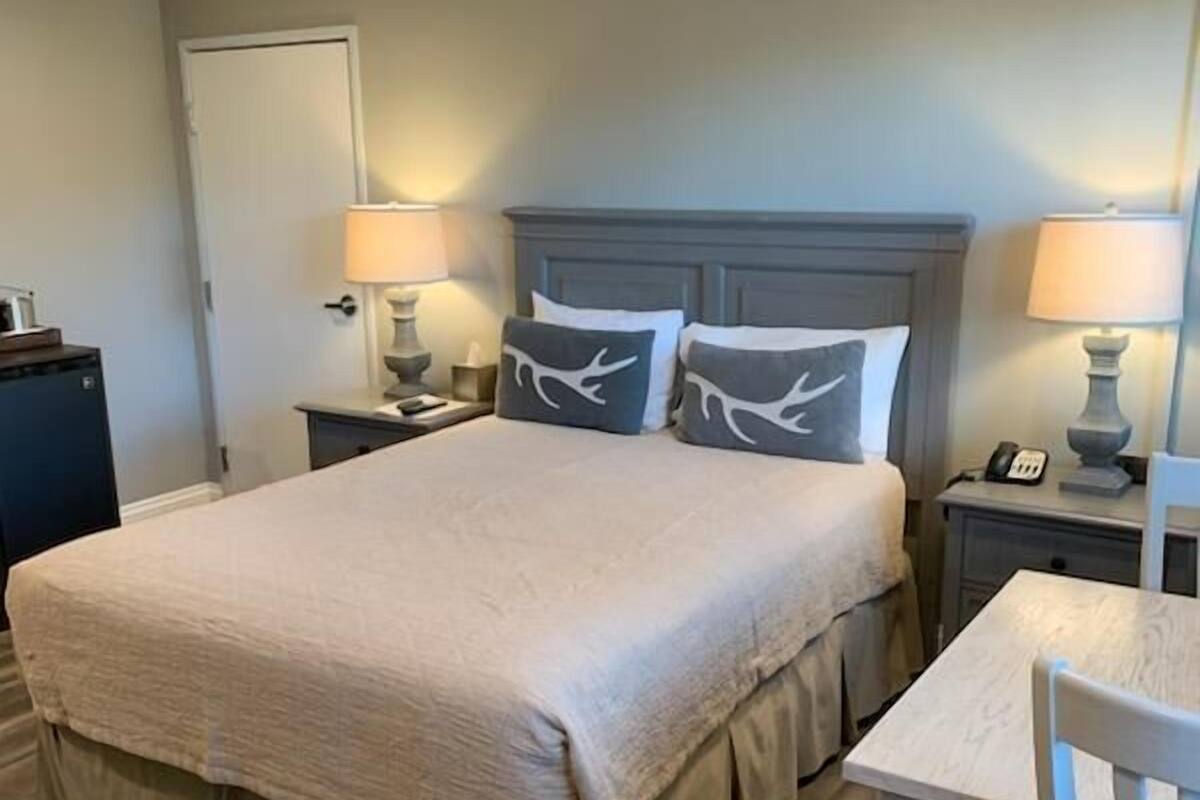 A hotel room with a large bed, bedside tables, a desk, and a chair.
