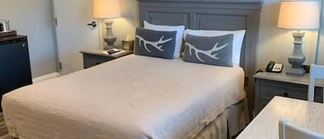 Een hotelkamer met een groot bed, nachtkastjes, een bureau en een stoel.