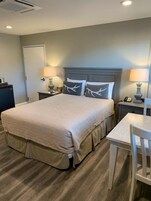A hotel room with a large bed, bedside tables, a desk, and a chair.