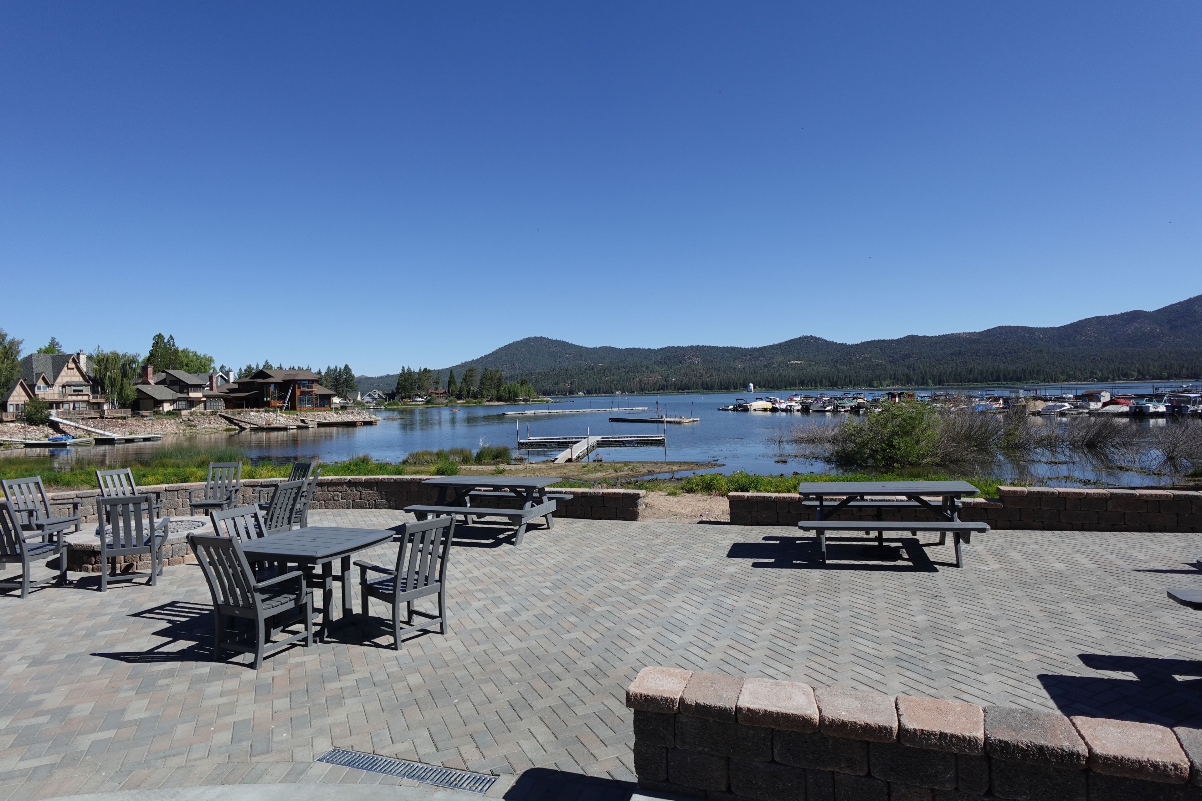 An outdoor seating area with tables and chairs overlooking a lake with boats and docks.