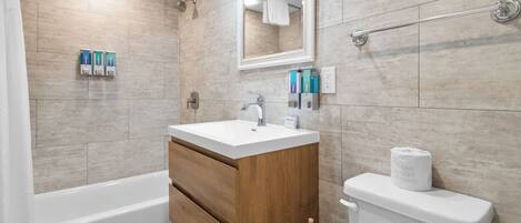 Un baño moderno con un tocador de madera, un lavabo blanco y un inodoro.