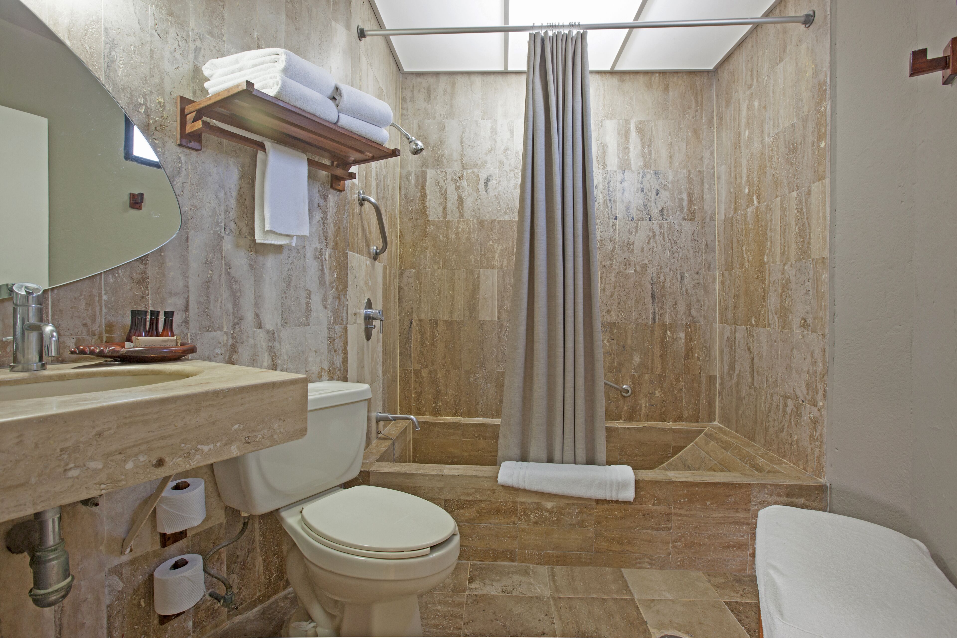 A bathroom with a shower, toilet, sink, and a mirror.