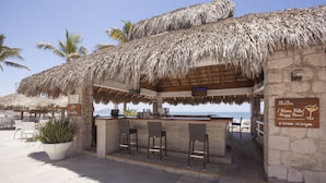 A beachside bar with a thatched roof, stone walls, and a view of the ocean. - Gaviana Resort (Mazatlán)