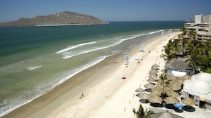 A beach with a clear view of the ocean, a sandy shore, and a mountain in the distance. - Gaviana Resort (Mazatlán)