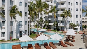 A modern hotel with multiple white buildings, a swimming pool, and lounge chairs. - Gaviana Resort (Mazatlán)