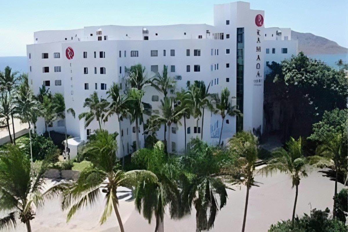 Un hotel moderno con fachada blanca, varios pisos y una entrada central.